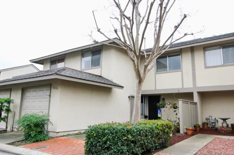 A well designed villa with a large front yard and a dried up tree