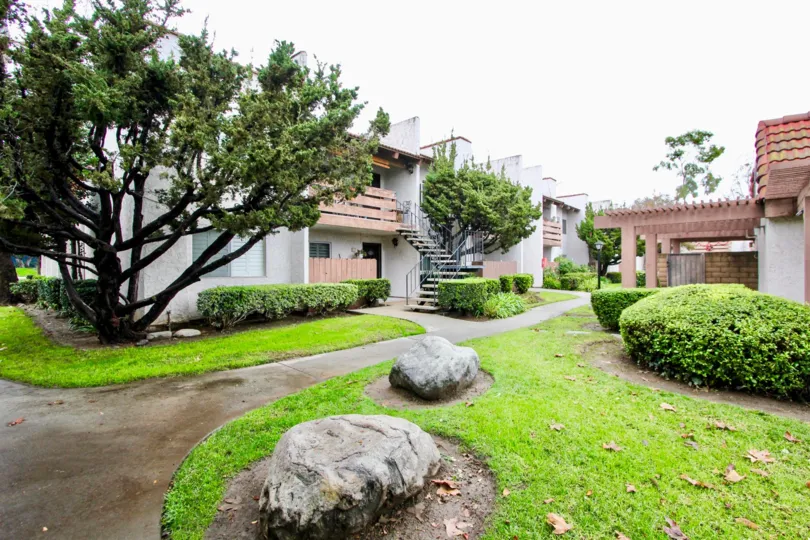 An overcast day in a Quail Meadows complex with trees, bushes, and grass all around each building