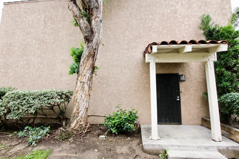 A private entrance to a two story residence at Rancho San Juan with tall tree and covered patio