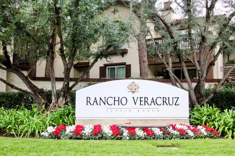 Large decorative community sign with professionally gardened flowers and mature trees in Rancho Veracruz