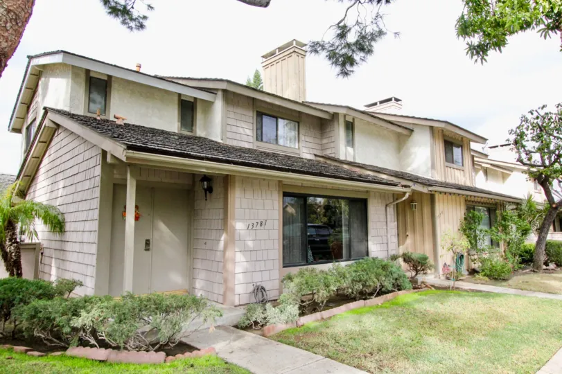 Front view of residences in Tustin Influential Square in Tustin, California. Grass, trees and shrubbery adorn the outer area.