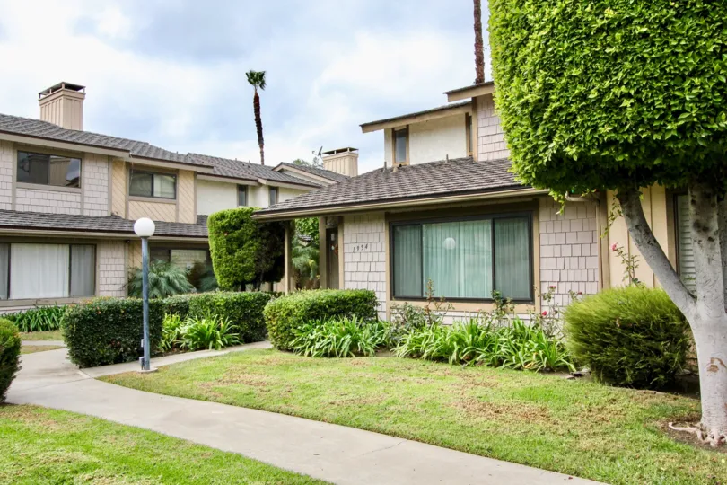 Middle class apartments under a clear sky. Community style homes with big windows and lawns.