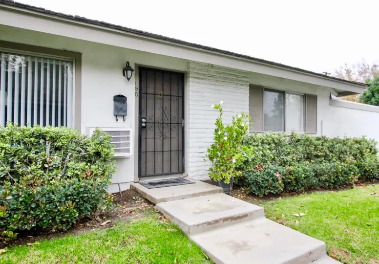 A simple bungalow with gated front doors and white walls in the Sycamore Gardens community.