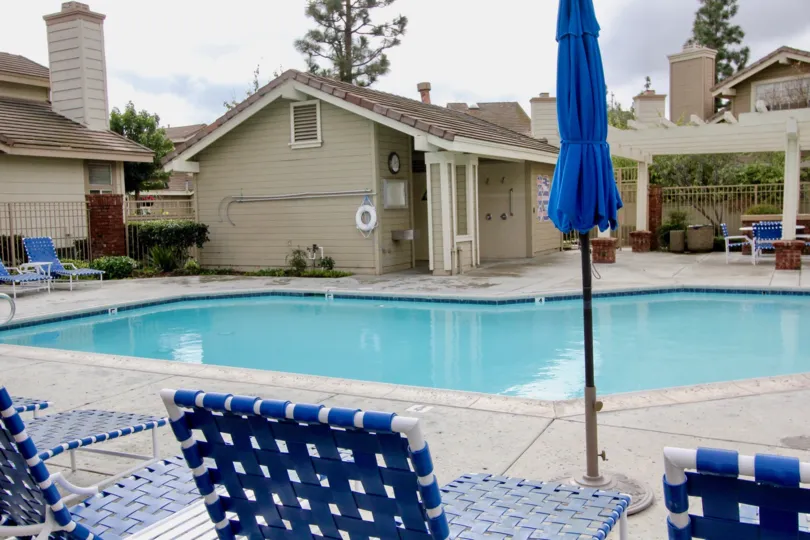 Moderate sized pool with adjacent deckspace and change room building and blue themed patio chairs in Sycamore Glen