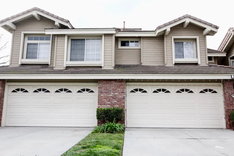 Large beige house with two two-car garages on an overcast day