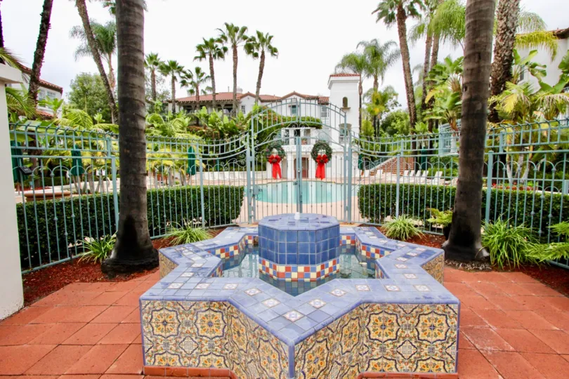 An overcast day by a Tustin Del Verde pool entrance with a colorful star pattern in front of the gate and Christmas wreaths on the gate