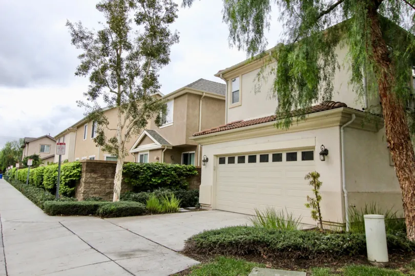 A sunny day at Tustin Field with two garage parking, green landscaping and tall trees
