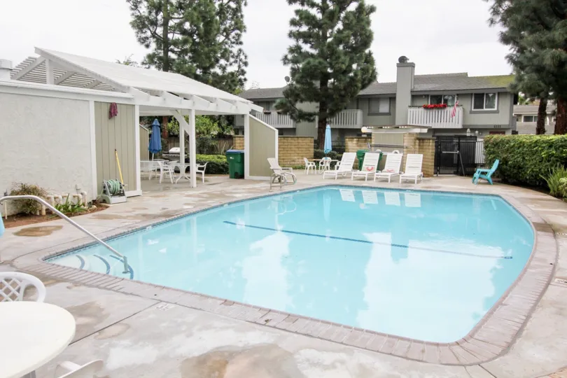 A round white patio table sits on a patio near a pool in the Tustin Pines community