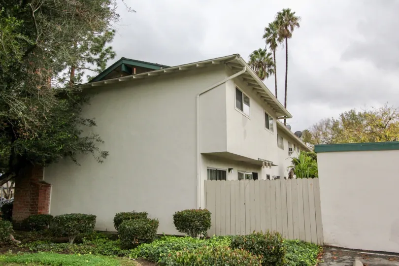 Three tall palm trees sit high above a residential building in the Tustin Place community
