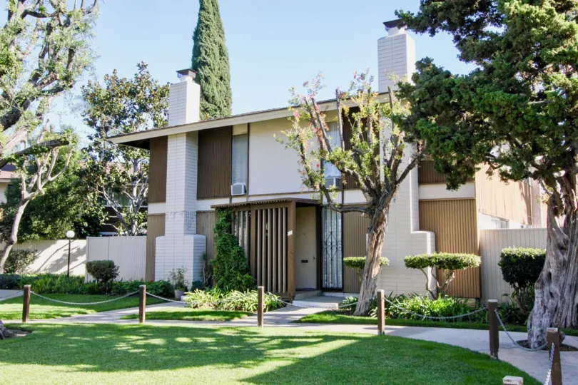 THE BUILDING IN THE TUSTIN VILLAGE WITH THE AIR CONDITIONER, LAWN, PLANTS, TREES
