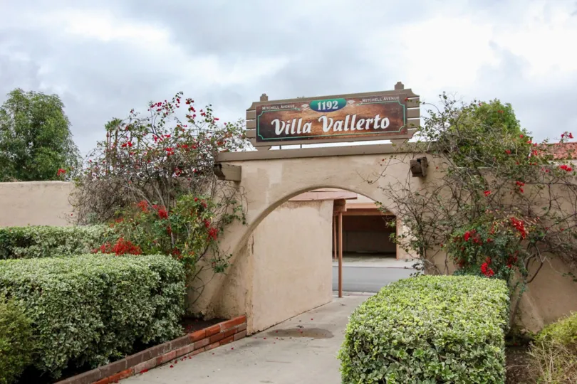 A sunny day showing the entrance to the private parking at Villa Vallerto with flowers and green bushes
