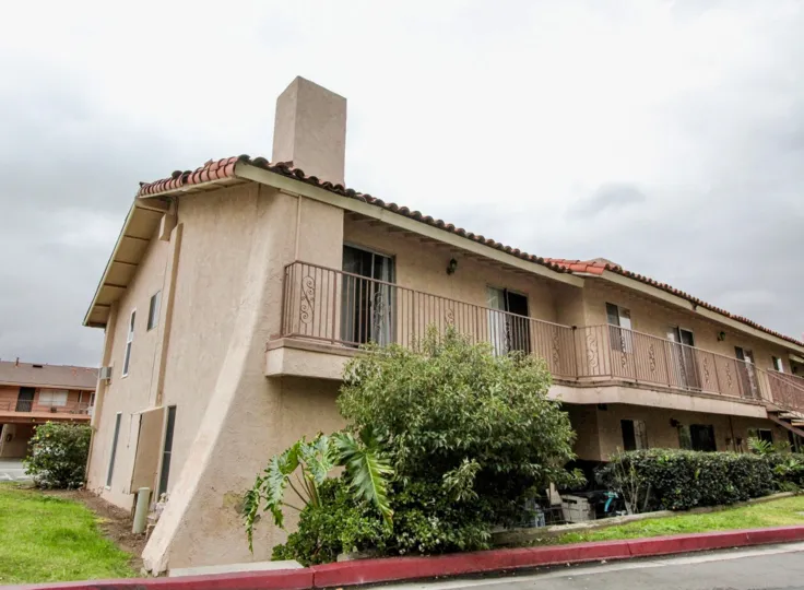 Apartment building in the Villa Vallerto community in the city of Tustin, California on an overcast day with foliage out front