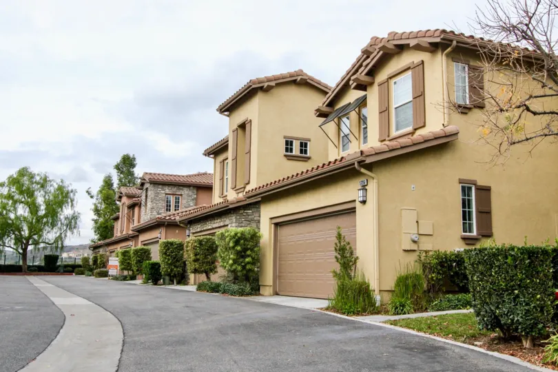 Beige two story Canterbury homes with brown garages in a row.