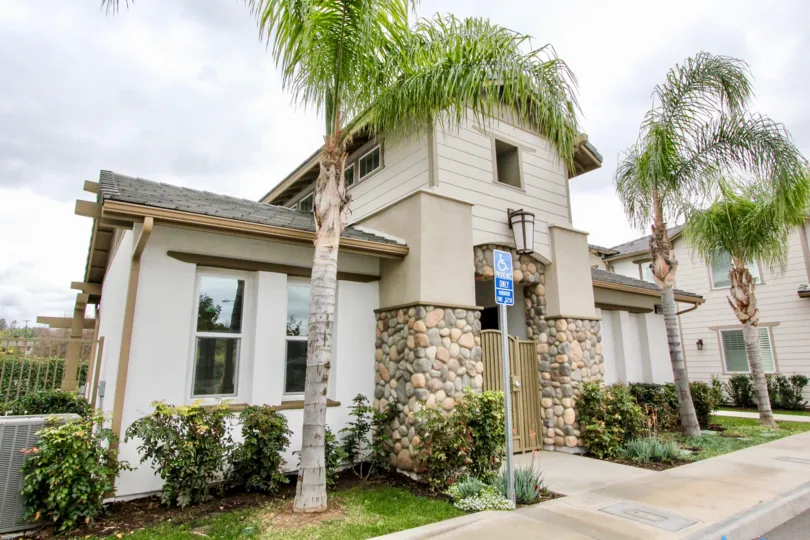 A white two story gated building in the Covington Classics with palm trees.