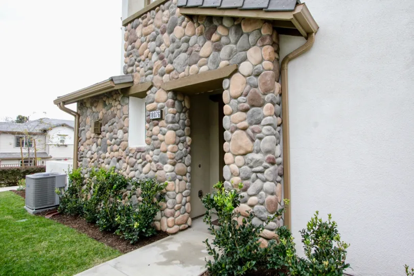 Entrance of door is made up of rocks with number board and bushes in Covington Classics