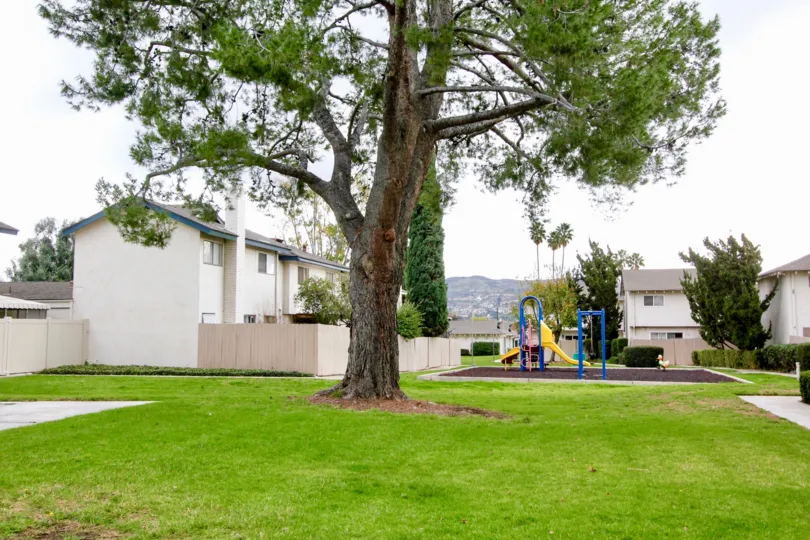 A large lawn outside a villa with children's park area inside the Fairgreen Homes community