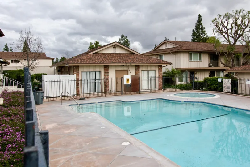 A fenced in pool and hot tub in Jamestowne Homes on a cloudy day,