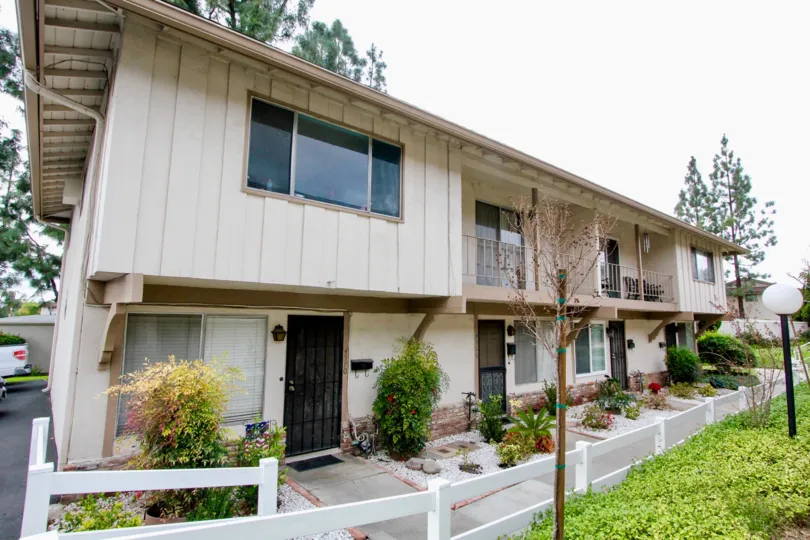The greay color house in the Jamestowne Homes with a beautiful flower garden, trees, ornamental plants and shrubs.