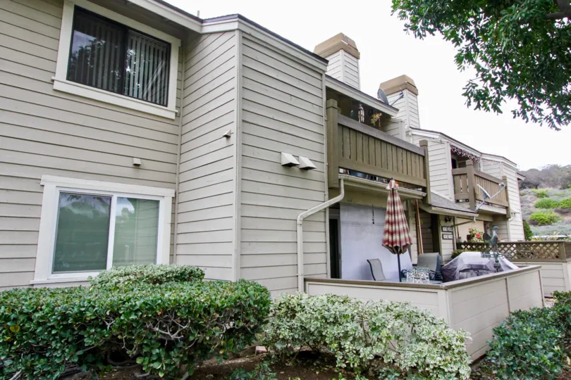 A two story apartment building in Kelllogg Terrace with patio chairs and a umbrella.