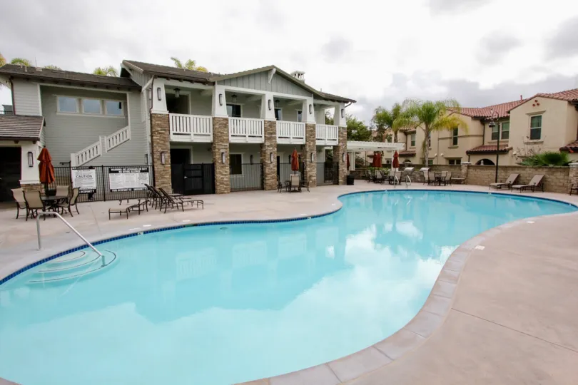 A pool in the Community: Palisades at Vista Del Verde with deck chairs and a stone fence.