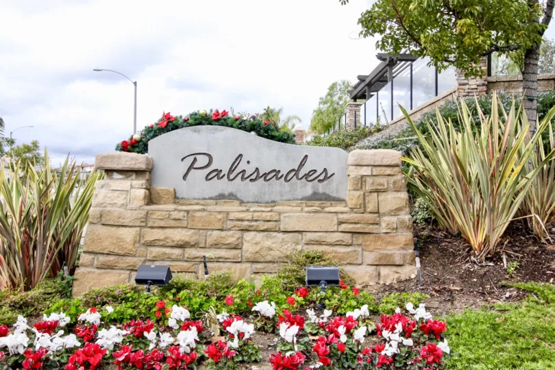 A cloudy day in the Palisades at Vista Del Verde in front of a sign and flower.