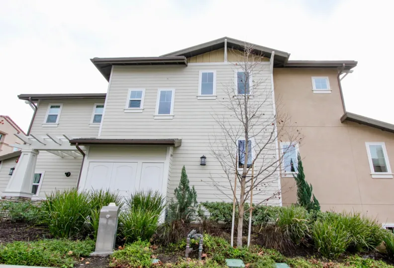 A very large house that is a light color with plants around the house in Palisades at vista del verde community in yarba linda, california.