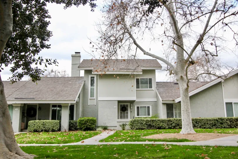A sunny day in the Rancho Dominguez Townhomes with ash color building and big tree.