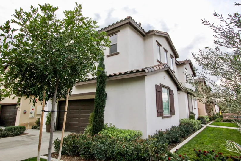 A white home in Rose Court with trees and a driveway on a cloudy day.
