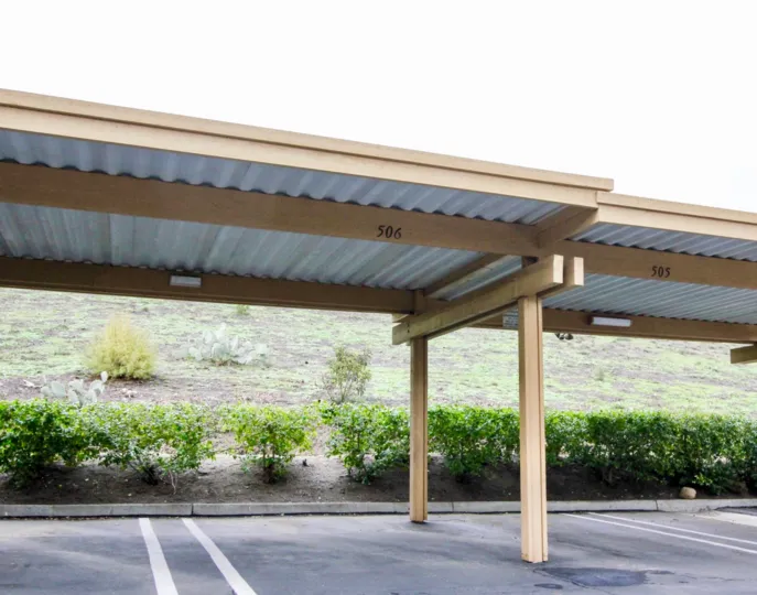 Covered parking spaces of The Hills with bushes on a cloudy day.