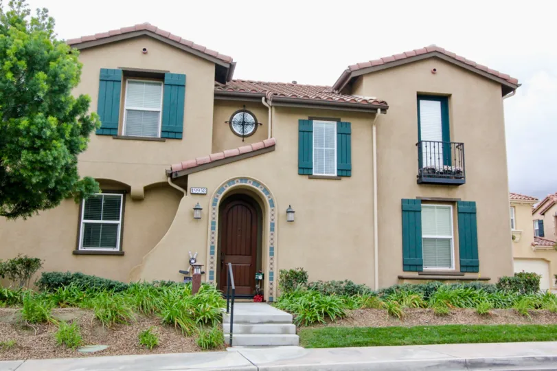 A two story Villaggio home with stairs and blue shutters on a cloudy day.