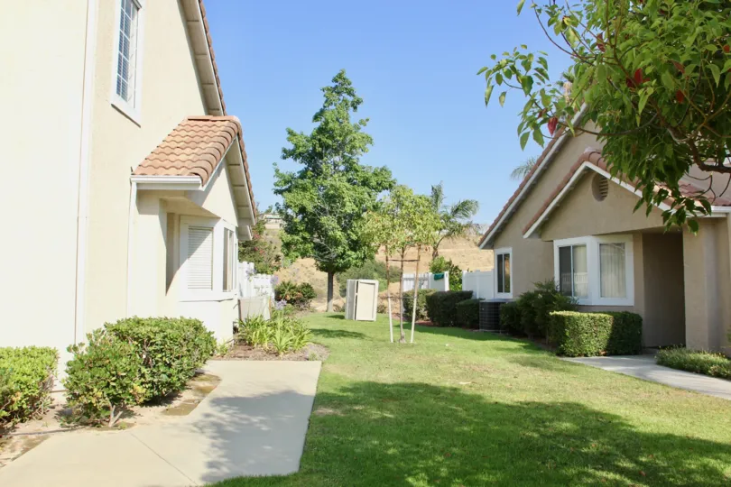 A garden infront of two houses with trees beside each one in Bella Vista community