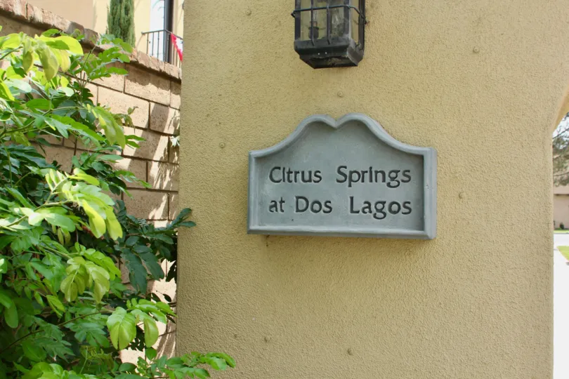 A decorative sign sits on a wall under a lamp at the Citrus Springs community.