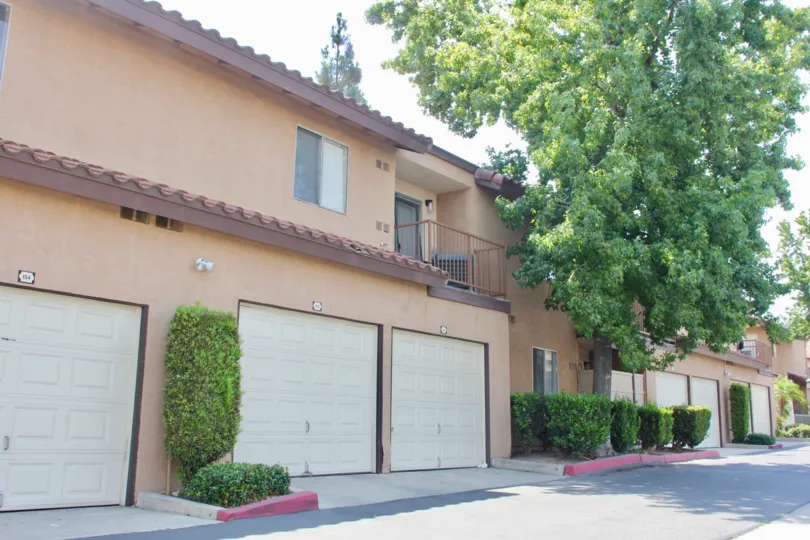 Garage area with several large trees and trimmed hedges along the road