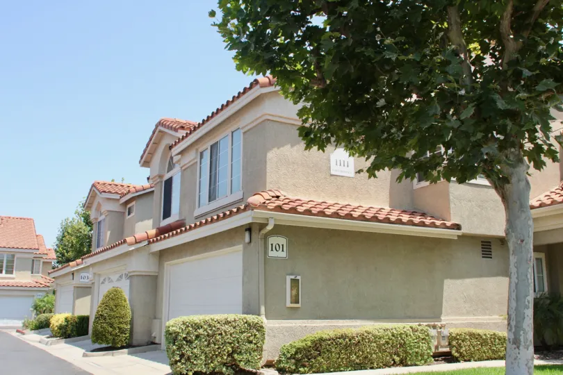 The house is covered with full of trees and grass and the door is locked and the house number is labeled at 101