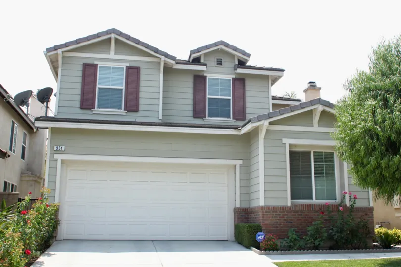 Front house with garage and rose bushes with beautiful tree and gardens