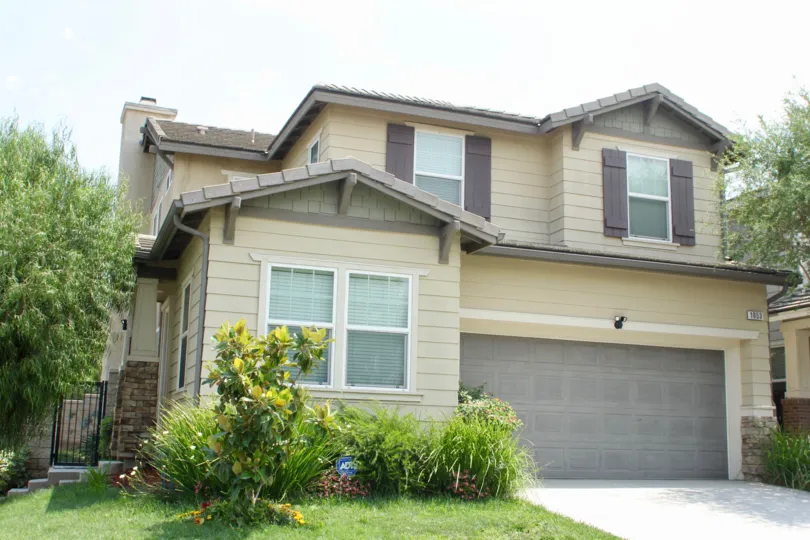 Garage with landscaping and crafsman house with large garage and shutters on windows