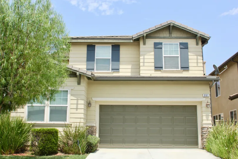 Large garage face for the house with trees shrubs and grass for landscaping