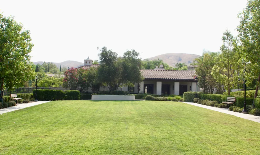 there is a beautiful garden located with full of trees and grasses surrounding the house and there is a mountain at the back of the house