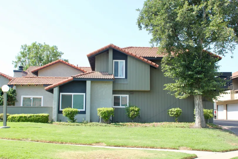 A red roof sits on top of a green vertical sided house at the Oakview community.