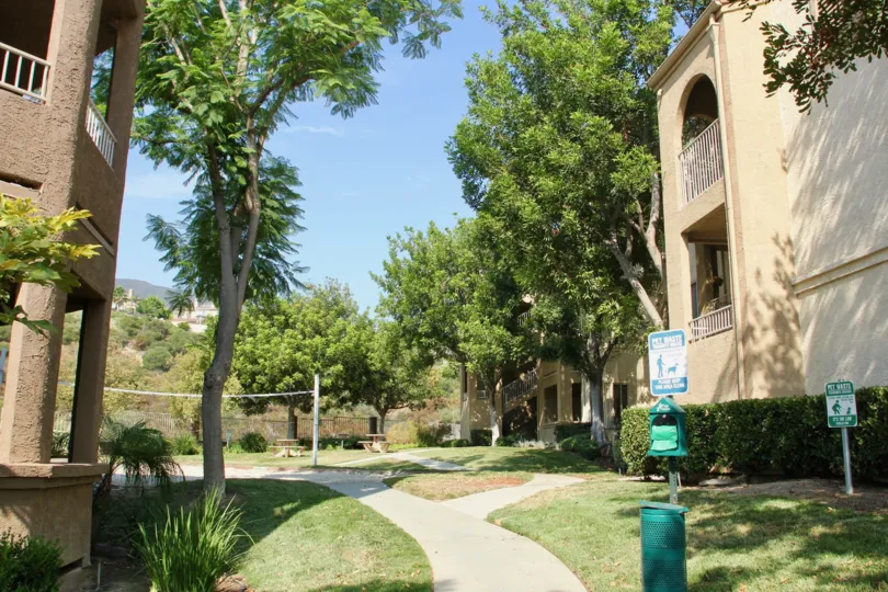 Garden pathway between condows has area for dogs with clean up bags, picnic tables and large trees for shade
