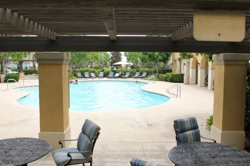 Two patio tables sit in the shade at the community pool of Serafina.