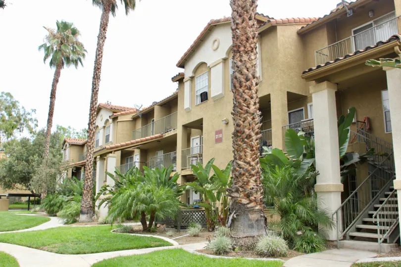 Condo adorned with large palm trees and banana trees, manicured lawn outdoor serenity
