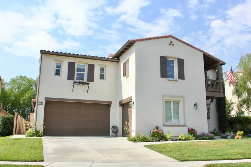 A neat yard frames a pretty white and brown house in Temescal Heights community.