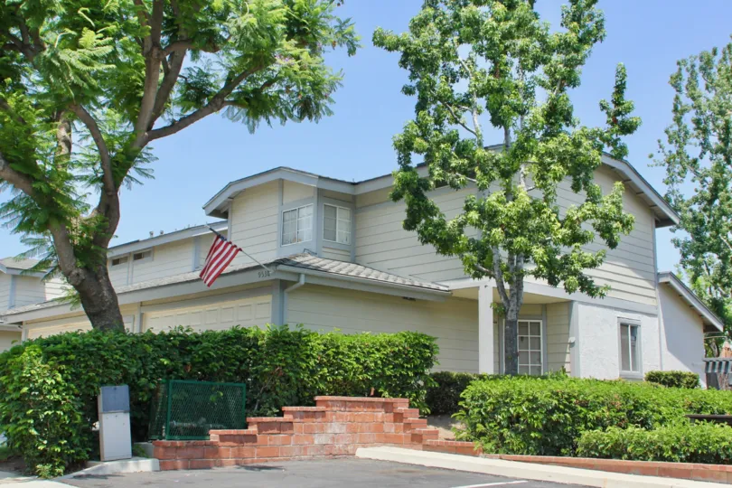 Trees and plants infront of a villa with american flag in The Gallery community