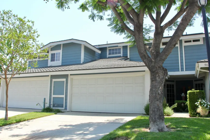Blue wooden walls, white garage doors and brown roof of The Gallery Apartment building, Corona, California
