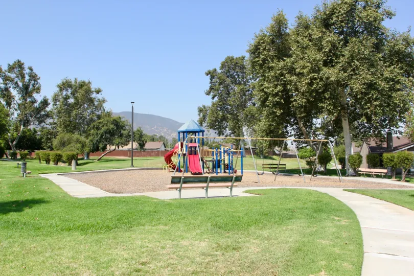 Childrens playground with slides, swing sets open grass, trees and picnic area with mountain view