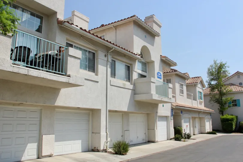 White condos with some shrubs and grassing with Spanish roofs and balconies