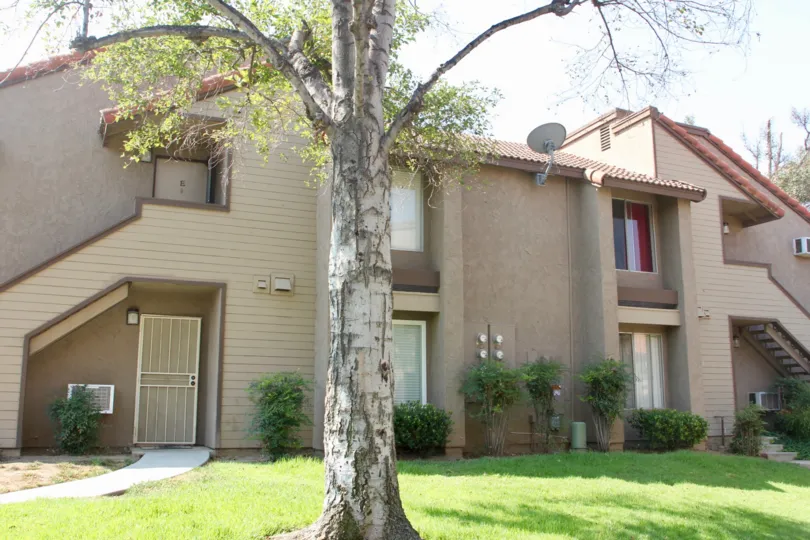 Large tree and shrubbery in front of this condo with slanted roof