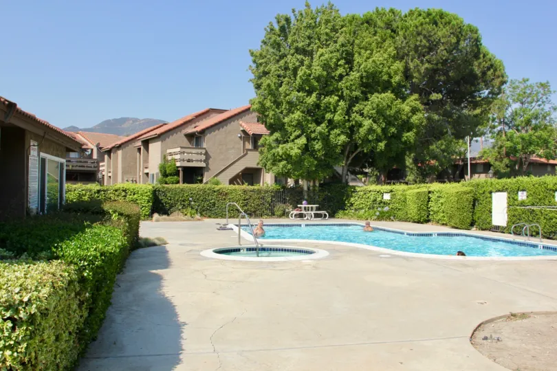 three persons are getting relaxation in water of swimming pool in house surrounded by grasses