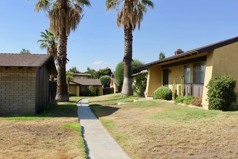sidewalk access and tall palm trees on a sunny day at the Pepper Tree Villas in hemet California